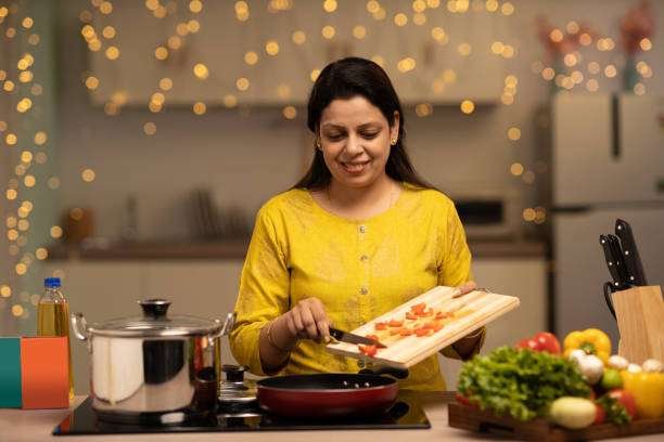 portrait-of-indian-woman-enjoying-while-cooking-meal-in-the-kitchen